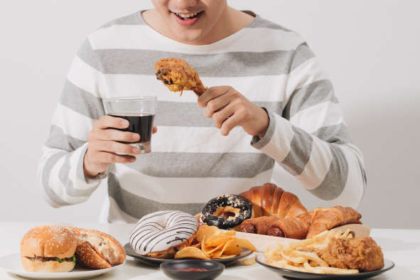 揚げ物やドーナツをたくさん食べる男性の写真